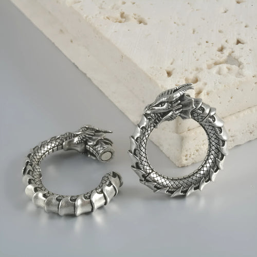 A pair of antique silver alloy earrings in a geometric dragon shape with hollow out design.