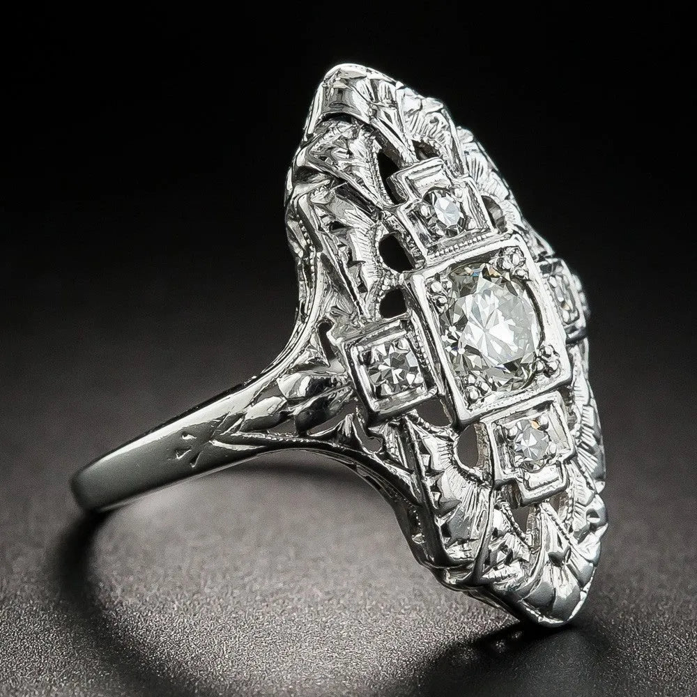 Geometric hollow-out silver ring with diamond studs on a finger.