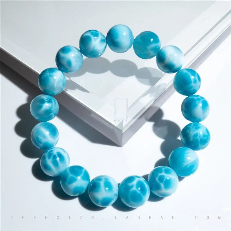 Blue handmade bodhi bracelet with natural sea-pattern crystal beads and pearl details on a wrist.