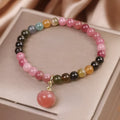 Natural rainbow tourmaline single-circle bracelet with agate peach pendant on wrist