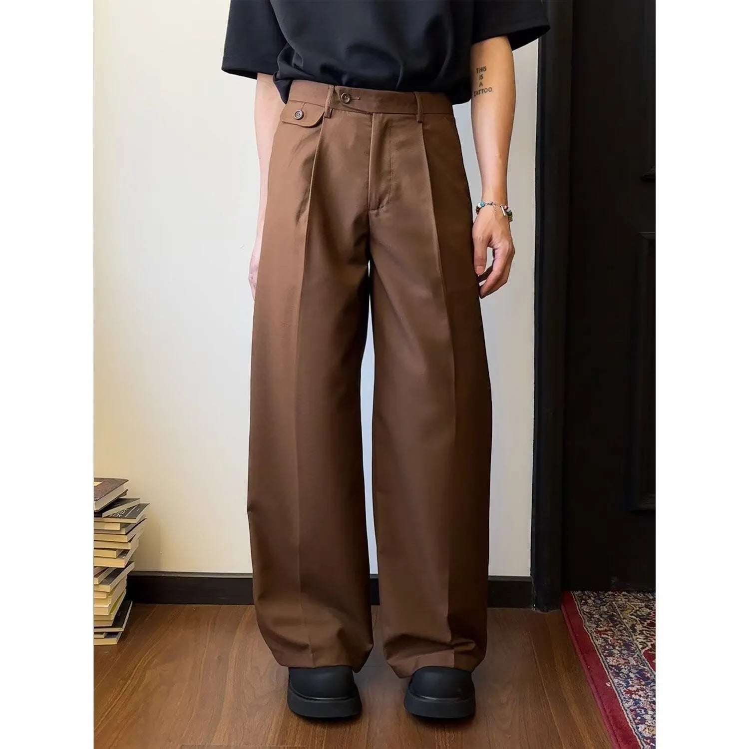Men's brown straight-leg wide-drape trousers on a hanger, showing loose fit.