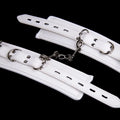 White PU sponge bondage set showing handcuffs, ankle cuffs, and a neck cuff on a neutral background.