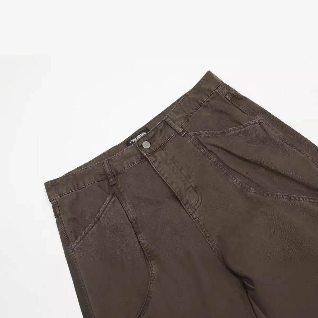 Men's loose straight-leg cotton trousers in brown, showing high waist and zipper fly.