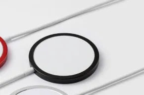 Silver metal Magsafe wireless charger for iPhone on a desk.