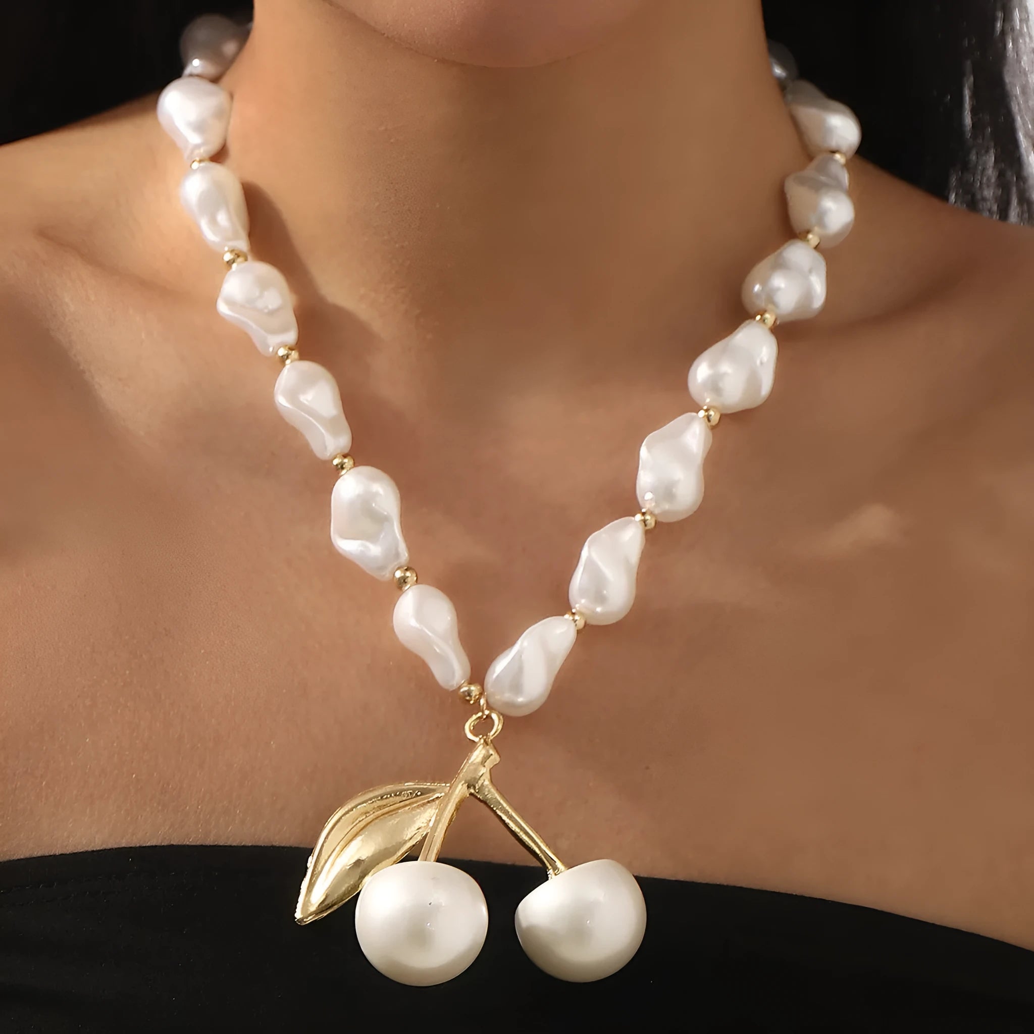 Gold and white alloy necklace with irregular cherry fruit and pearl pendant on a pearl chain.