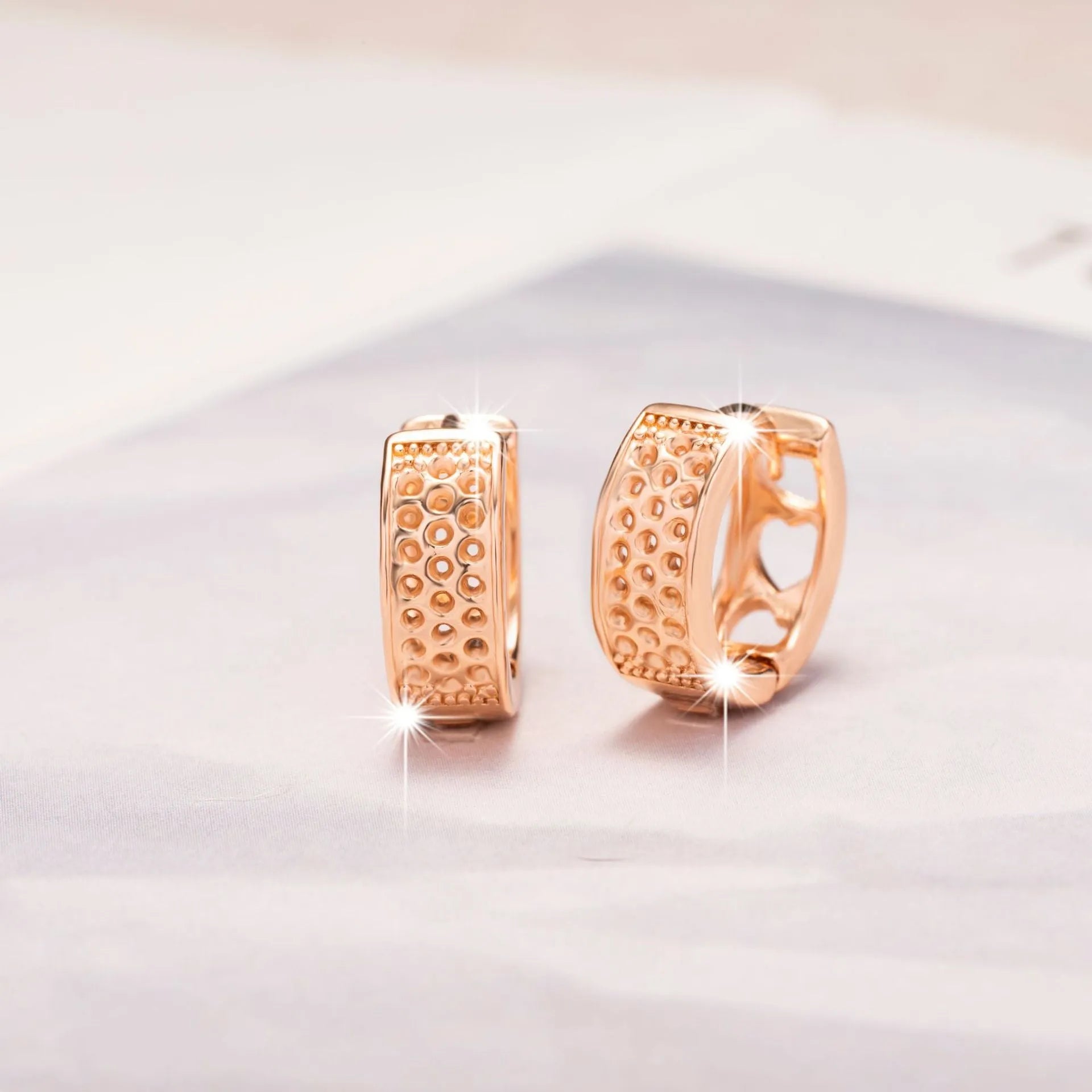 A pair of rose gold hollow heart-shaped earrings for women on a white background.