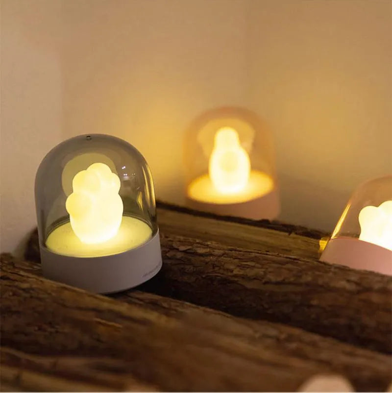 Grey cat paw shaped USB rechargeable night light and music box lamp on a desktop.