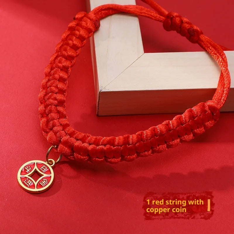 Adjustable hand-woven red rope pet collar with alloy lucky charm on wooden surface