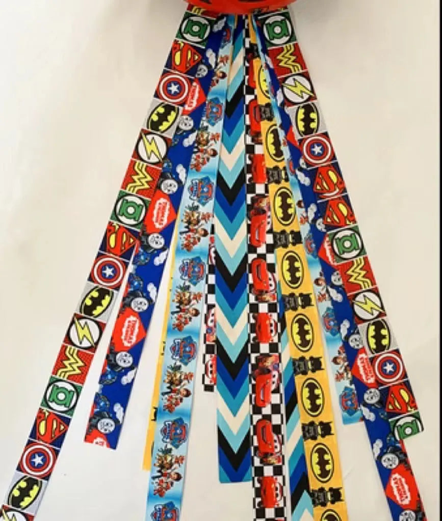 Colourful fabric helmet streamers for children's roller skating and ski helmets, shown in apricot, red, and grey.