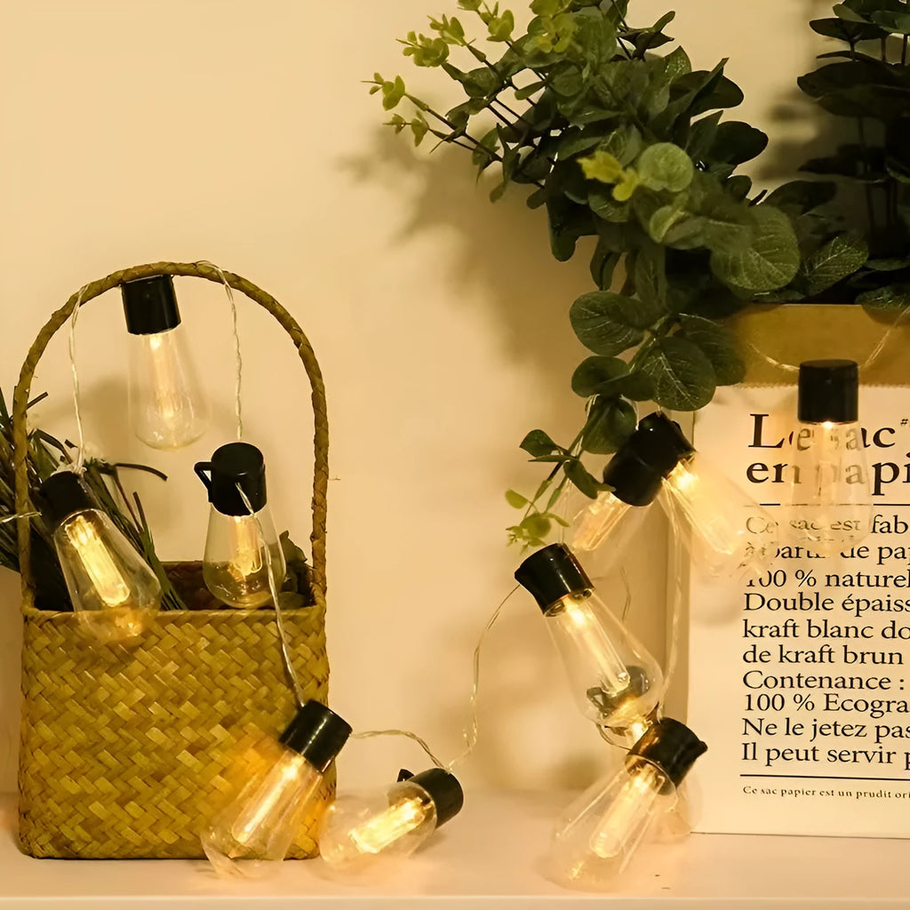 Waterproof outdoor string lights with retro glass bottle-shaped lamps hanging from a green wire.