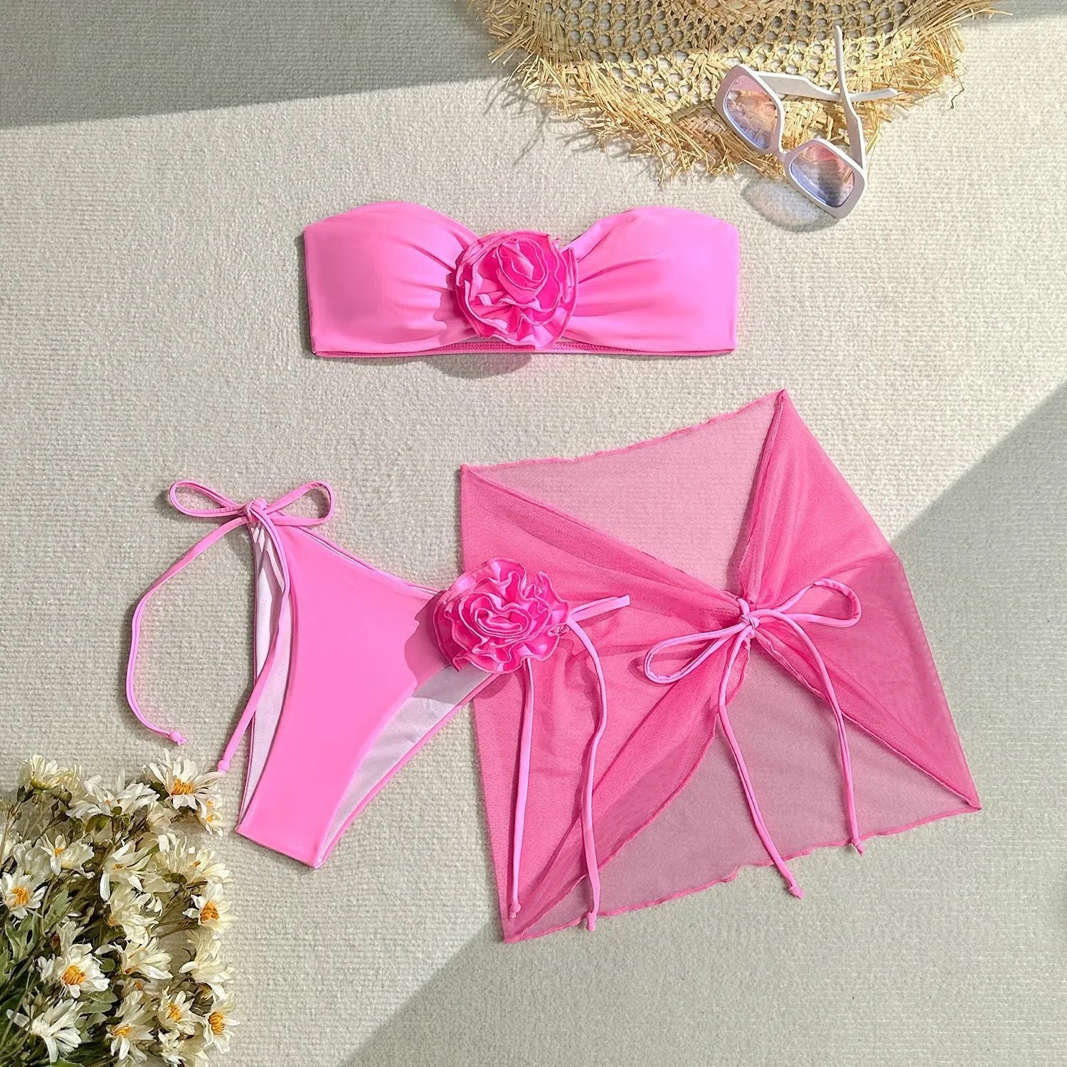 Blue women's tube top swimsuit with a large 3D tied flower, matching pants, and a skirt laid flat.