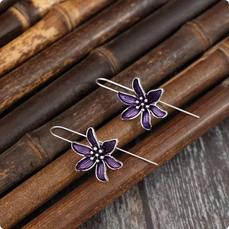A pair of purple flower-shaped alloy earrings with an electroplated finish.