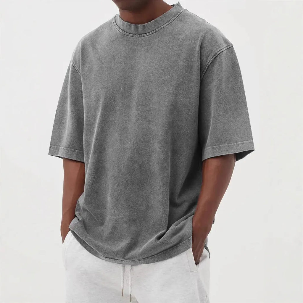 Man wearing a loose-fit, stone-washed polyester T-shirt in a solid colour with a distressed finish.