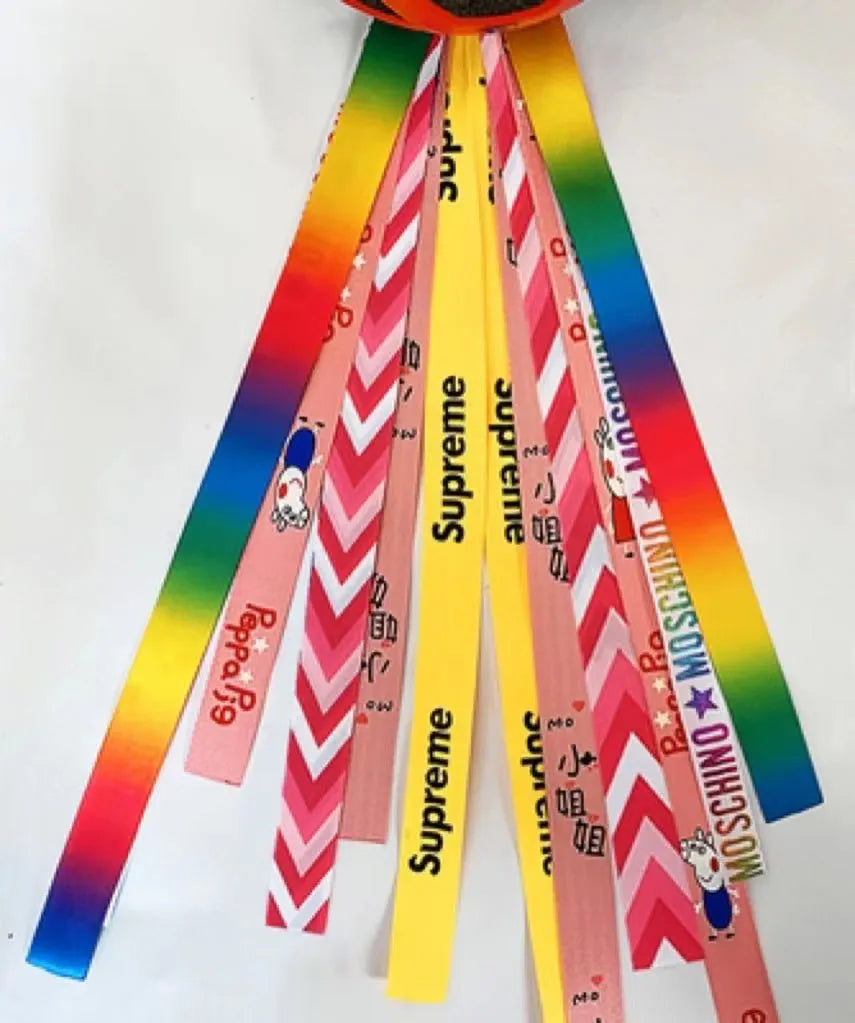 Colourful fabric helmet streamers for children's roller skating and ski helmets, shown in apricot, red, and grey.