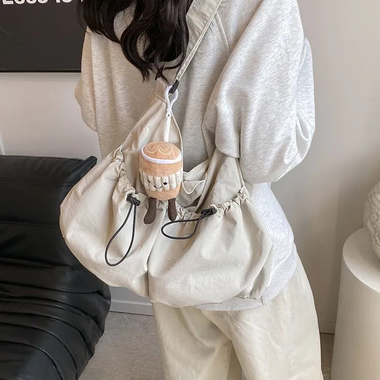 Pleated foldable polyester crossbody student bag in multiple colours showing split pocket and compact 35cm dimensions