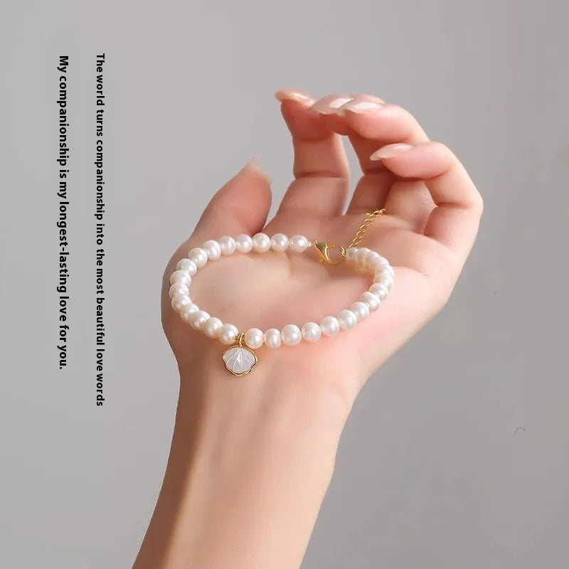 Women's freshwater pearl bracelet with a shell charm on a 16cm elastic string.