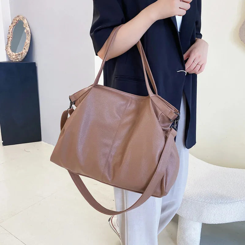 Large horizontal soft PU messenger bag in black with zip opening and long shoulder strap.