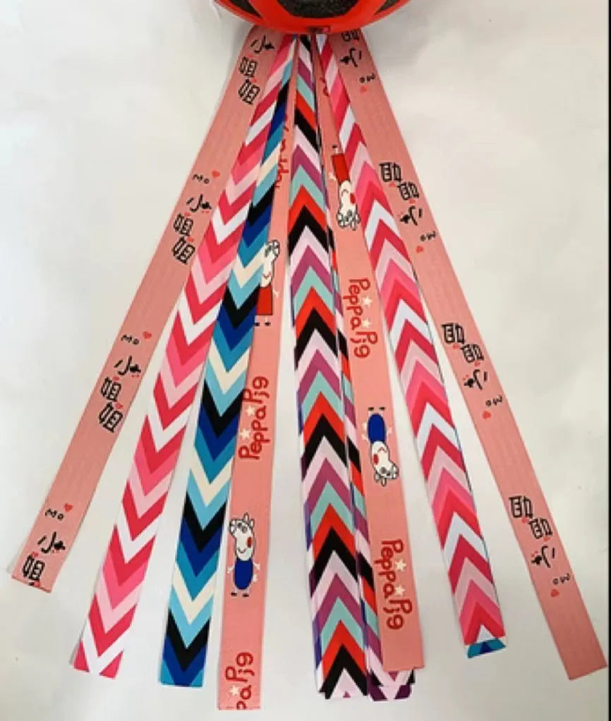 Colourful fabric helmet streamers for children's roller skating and ski helmets, shown in apricot, red, and grey.