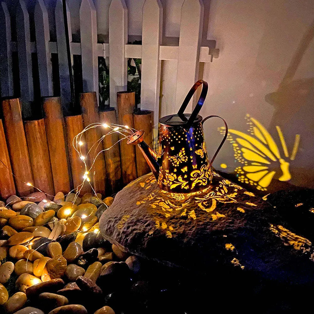 Tapered iron solar garden lantern with butterfly pattern emitting warm white light.