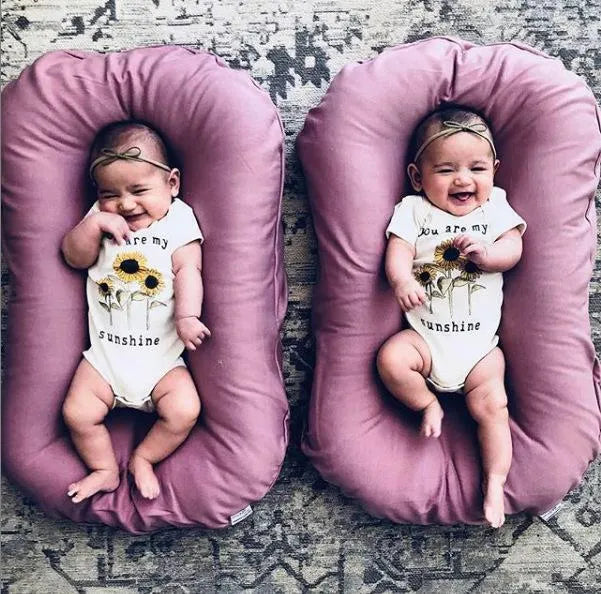 Beige portable baby nest crib for newborns measuring 75cm by 45cm on a neutral background.