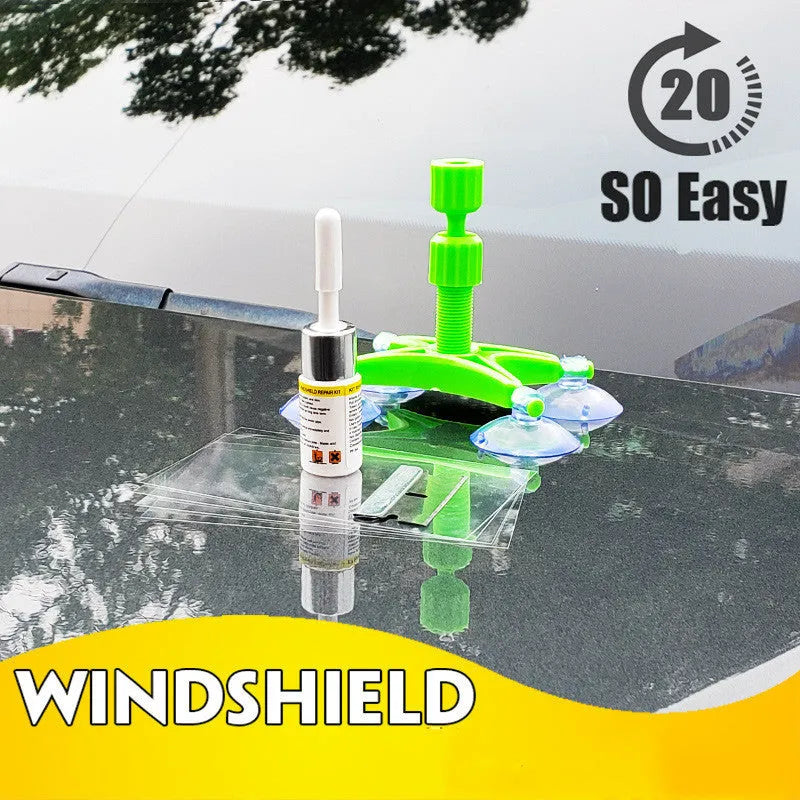 Windshield repair fluid kit with green resin, repair device, curing strips, and sleeved razor blade on a car windscreen