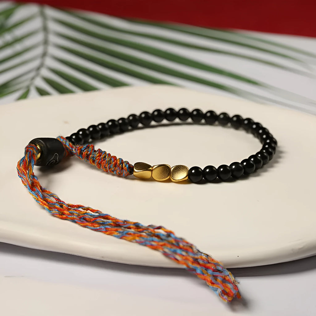 Hand-woven obsidian carrying strap bracelet with a stone bead, showing its 4mm width and adjustable length.