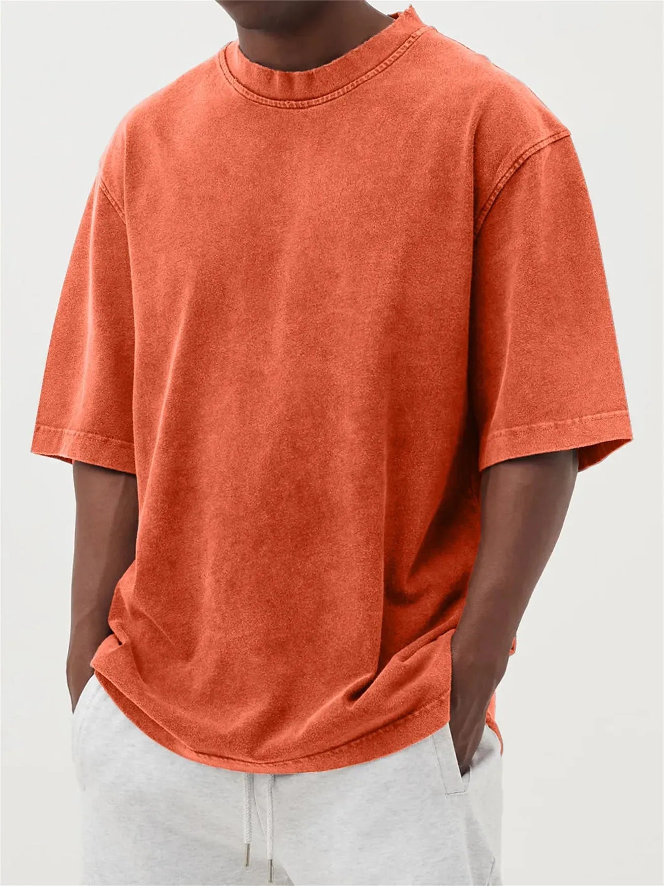 Man wearing a loose-fit, stone-washed polyester T-shirt in a solid colour with a distressed finish.