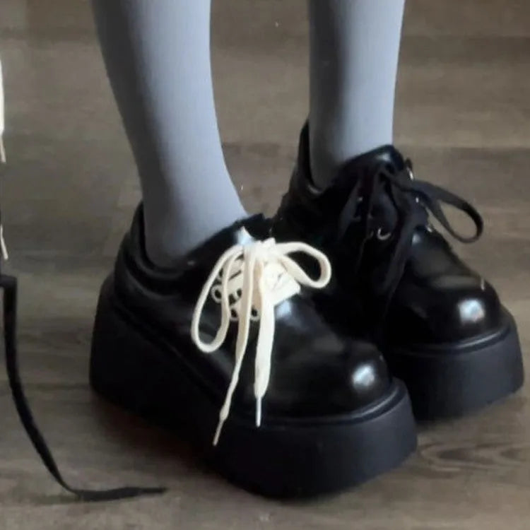 Women's matte black retro platform shoes with chunky rubber sole and lace-up buckle.