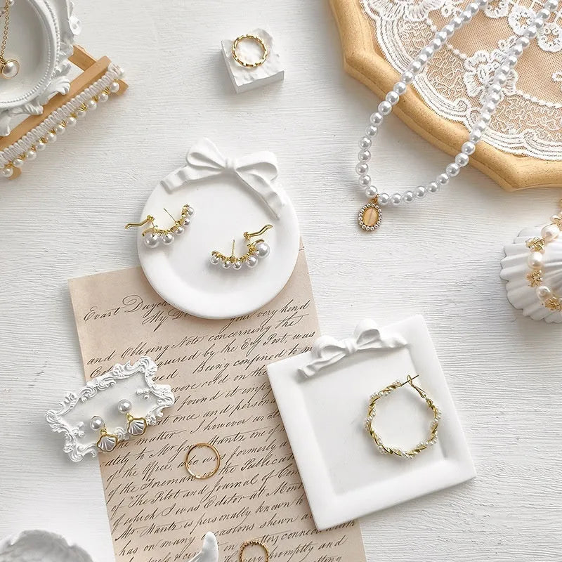 European Baroque style gypsum jewellery display plate with rings and earrings on a dressing table