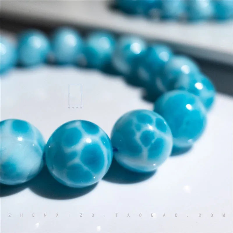 Blue handmade bodhi bracelet with natural sea-pattern crystal beads and pearl details on a wrist.