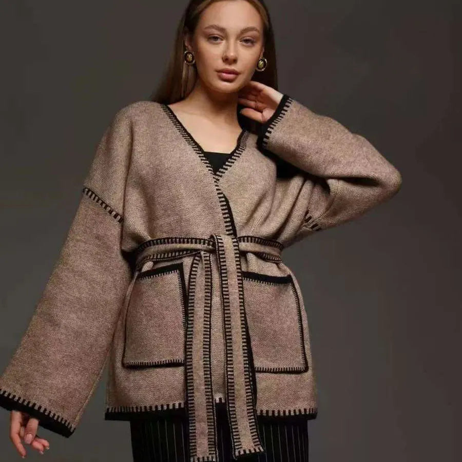 A loose, mid-length knitted cardigan with a front lace-up detail, shown in a camel colour.