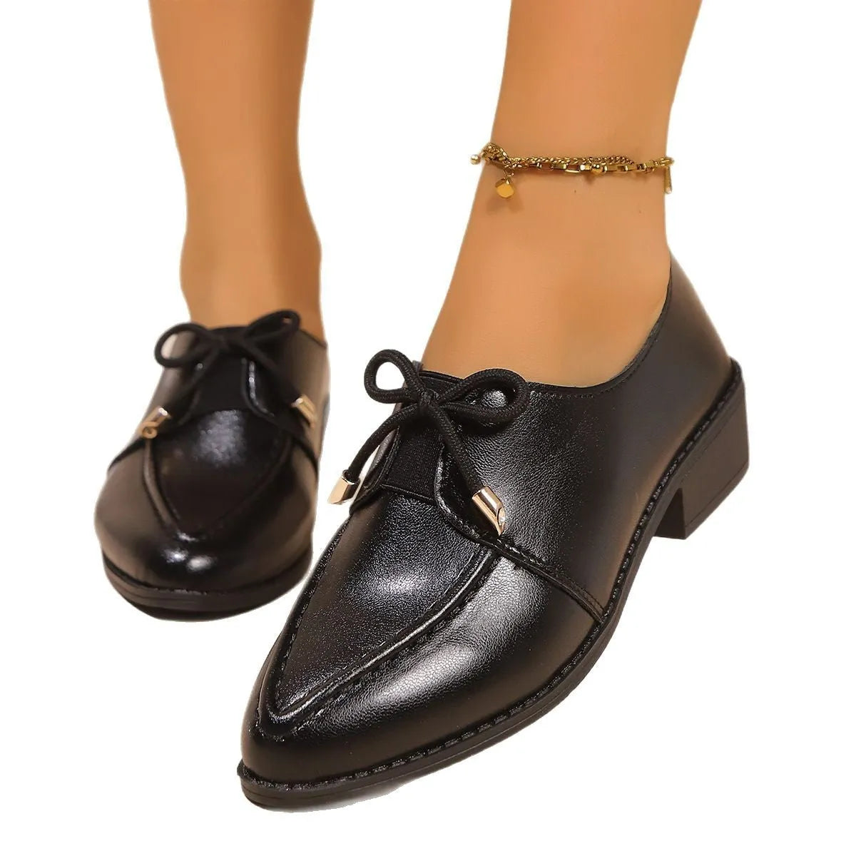 Women's brown slip-on flat shoes with a large bow decoration on the pointed toe.