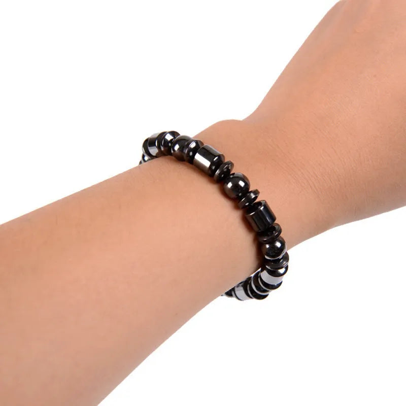 Black pentagram design magnetic therapy bracelet made from magnetite and hematite stones on a wrist.
