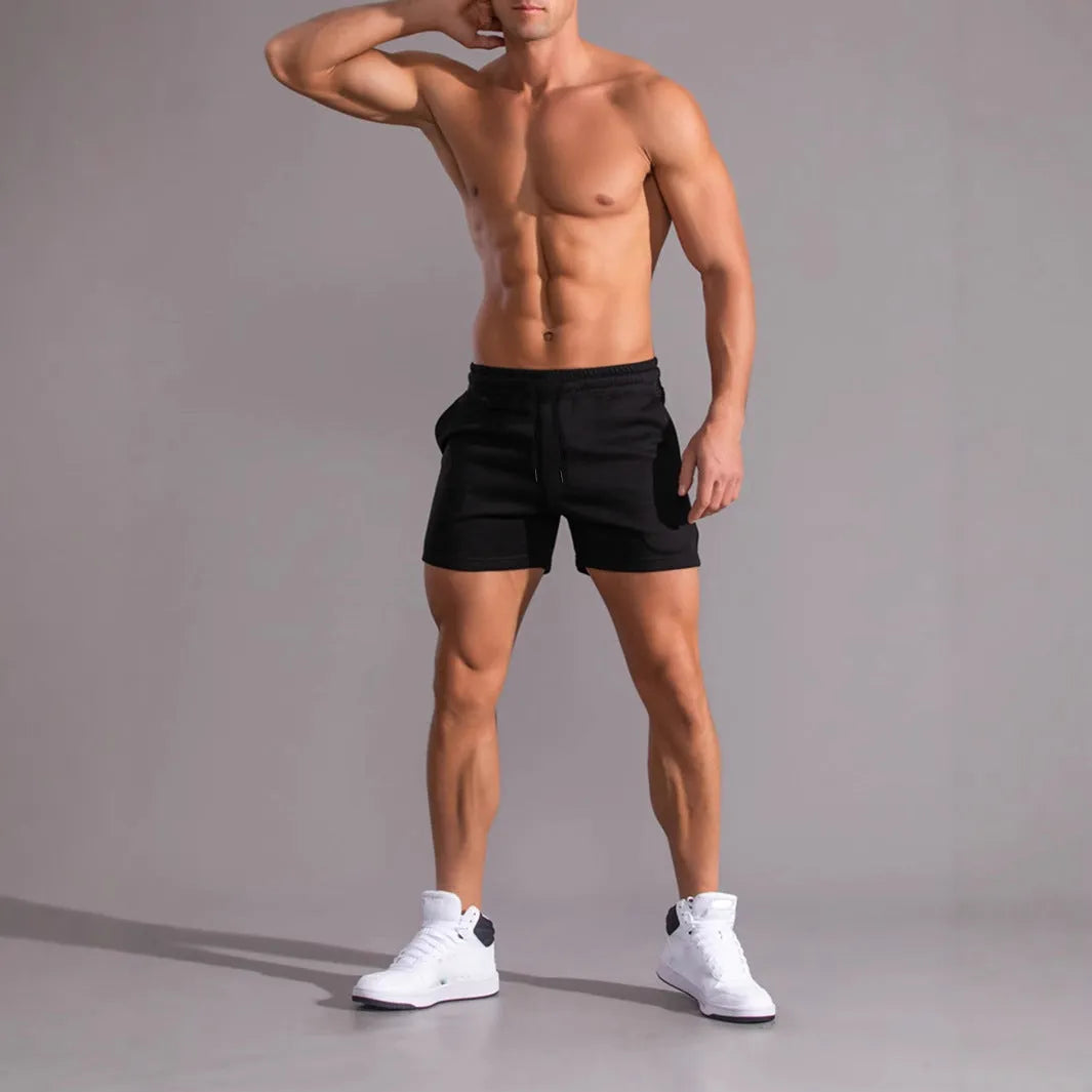 Pack of three men's solid colour drawstring shorts in black, khaki, and light brown on a hanger