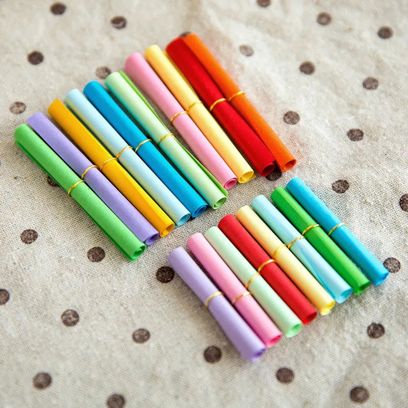 Multi-coloured mini paper scrolls in various sizes with metal eyelets for hanging.