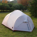 Grey outdoor multi-person tent with aluminium pole and 12 ground ropes set up on grass