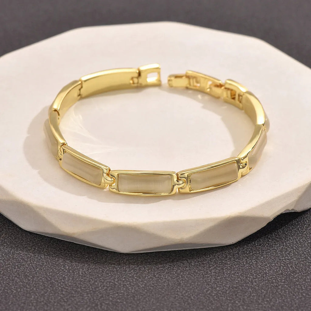 Women's geometric rose gold opal bracelet with quadrilateral shape and gemstone inlay on a plain background