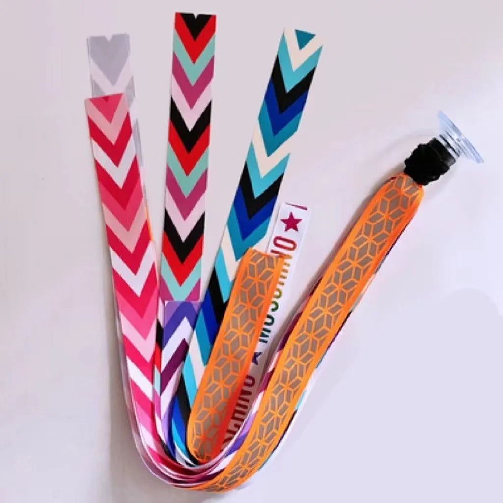 Colourful fabric helmet streamers for children's roller skating and ski helmets, shown in apricot, red, and grey.