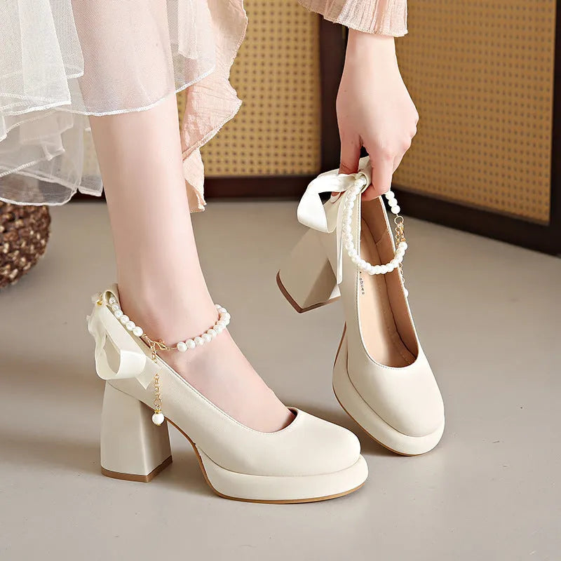 Women's beige Mary Jane shoes with a chunky block heel and an ankle-strap buckle on a round toe.