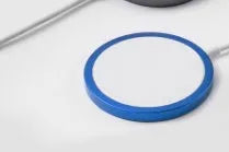 Silver metal Magsafe wireless charger for iPhone on a desk.