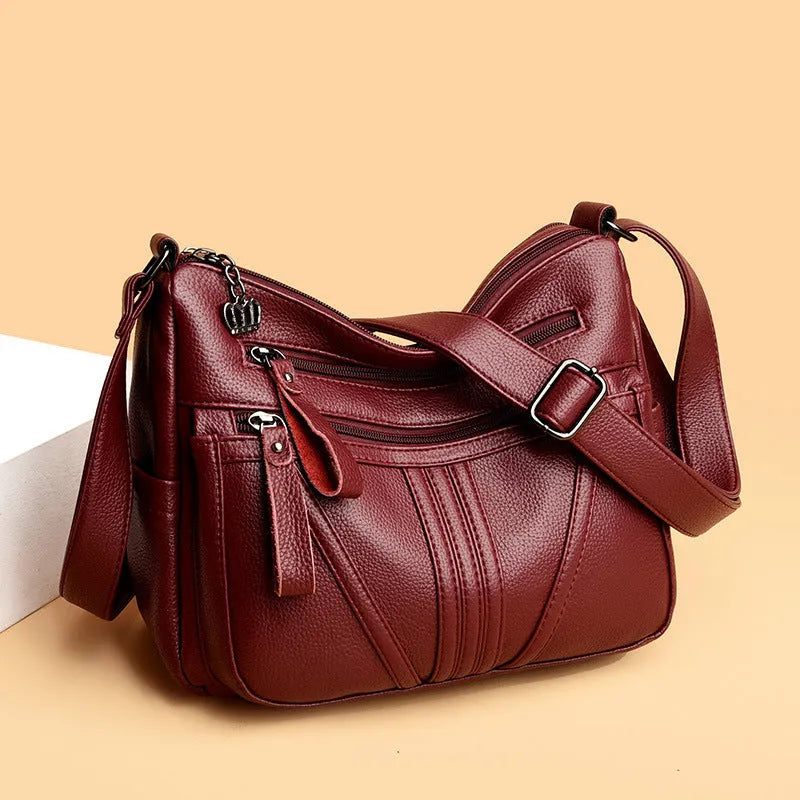 Genuine leather horizontal square messenger bag in black with contrast stitching and a front slit pocket.