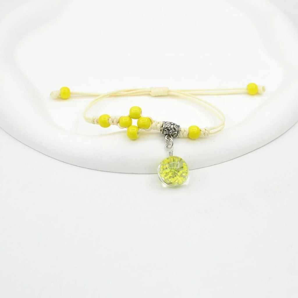 Close-up of a hand-woven glass bracelet with large beads containing real dried flowers and a lace design.