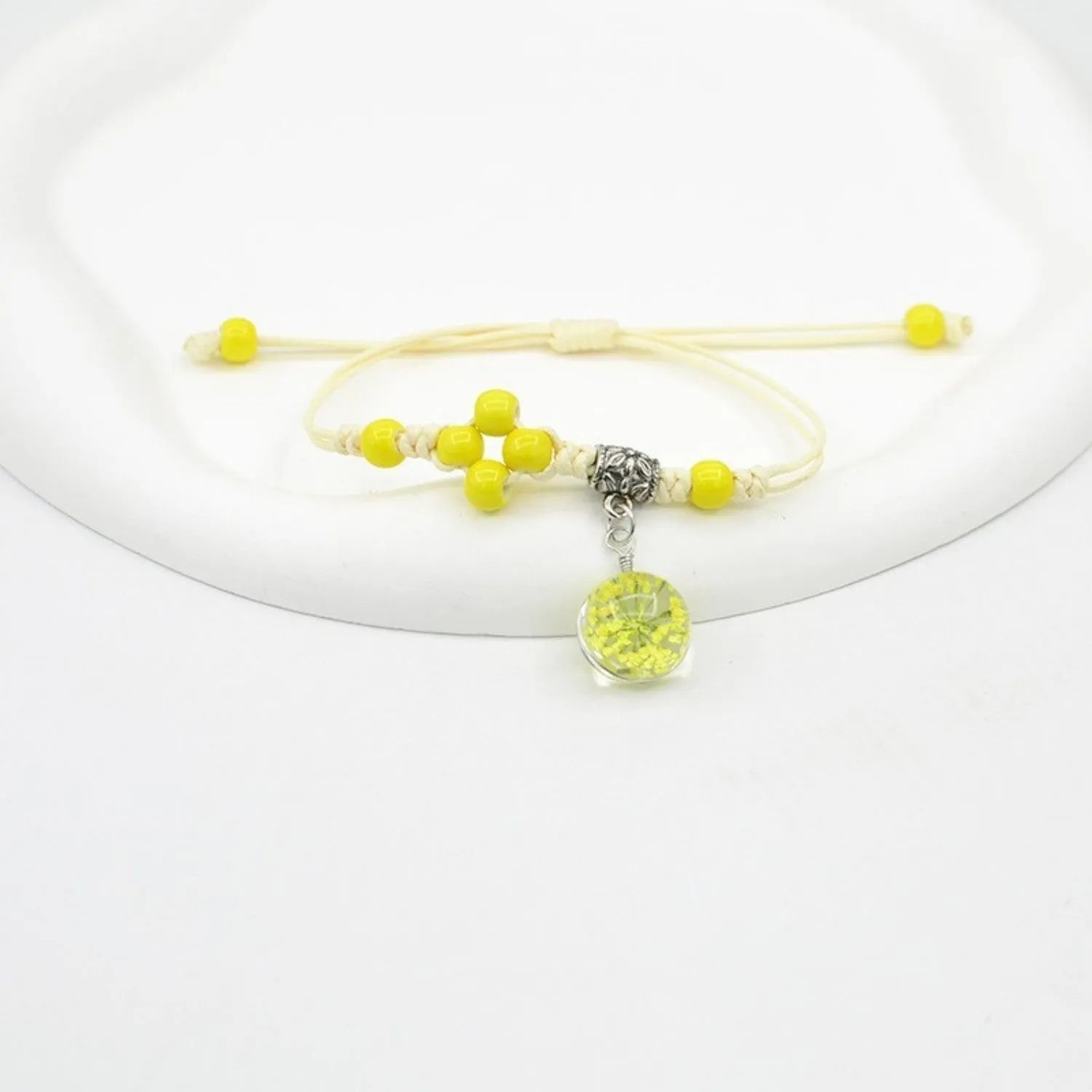 Close-up of a hand-woven glass bracelet with large beads containing real dried flowers and a lace design.