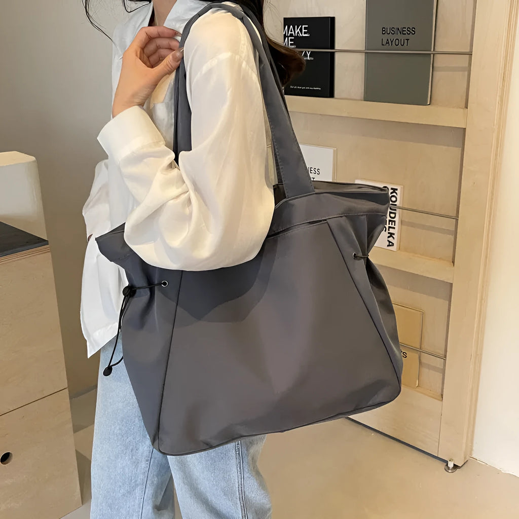 A foldable Oxford cloth commuter shoulder tote bag shown in one of five colours: black, brown, dark gray, light gray, or purple.