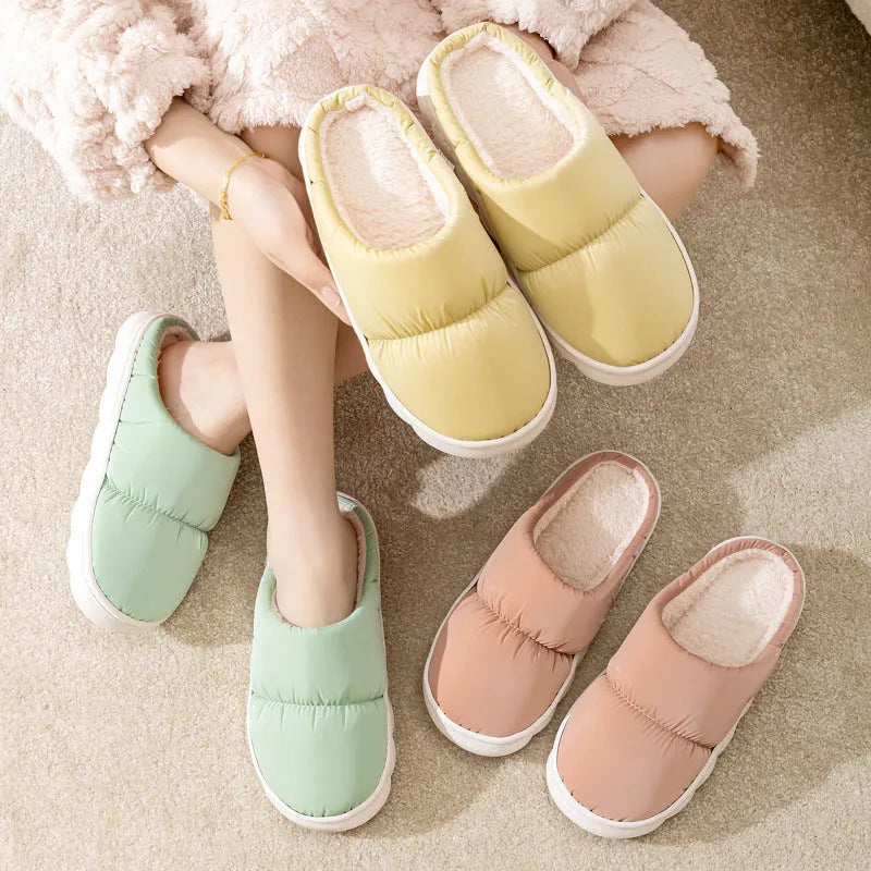 Pair of thick-soled indoor slippers in blue with a wrapped toe, low heel, and artificial plush lining.