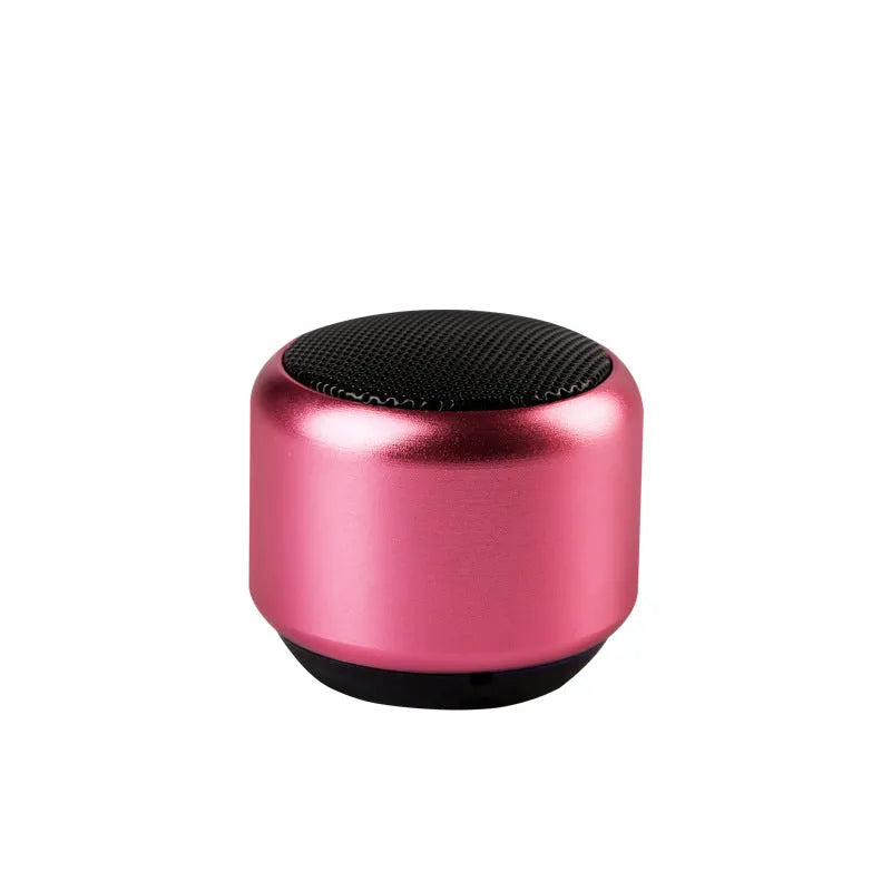 Small portable Bluetooth speaker in black, blue, gold, or pink colour on a table.