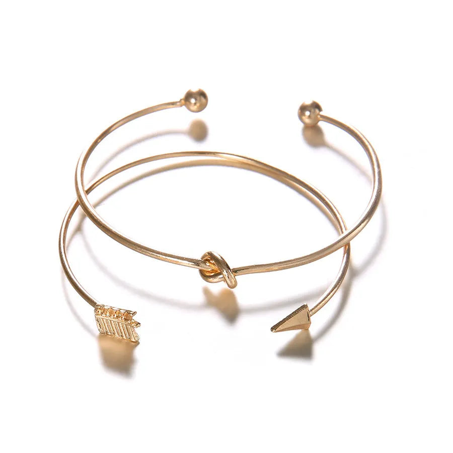 Gold vintage women's cuff bracelet with arrow and knotted design details.