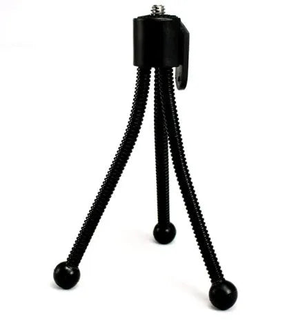Compact black iron frame mini desktop tripod with a ball head, shown folded and extended next to a smartphone.
