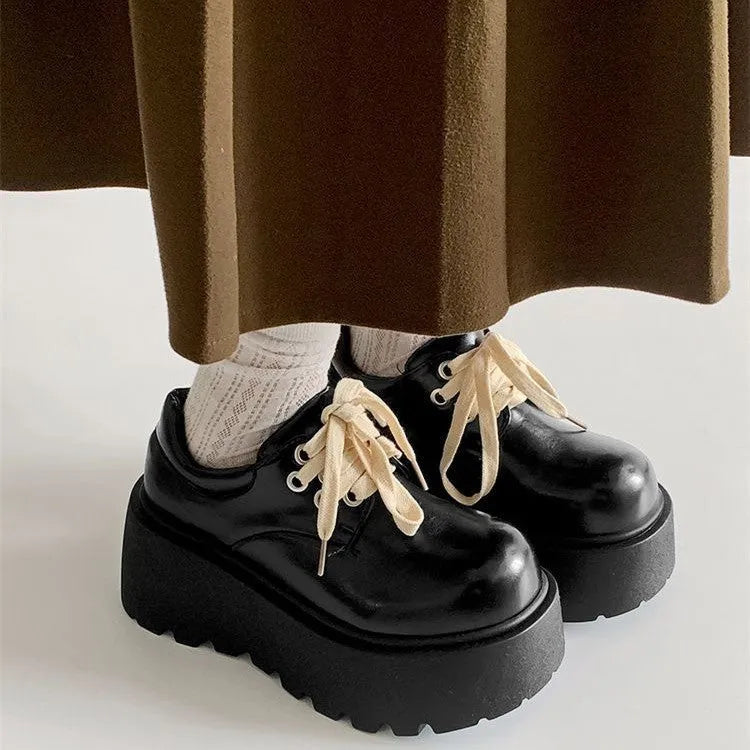 Women's matte black retro platform shoes with chunky rubber sole and lace-up buckle.