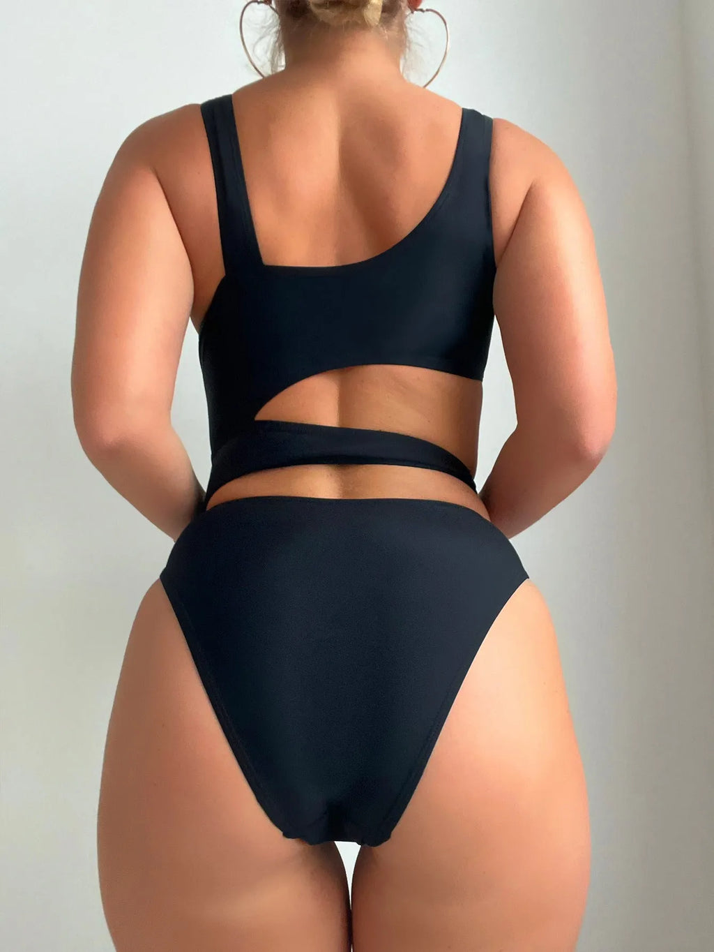 Black solid colour women's one-piece swimsuit with high-cut legs and a hollow back design.
